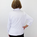 Person wearing a white shirt with long sleeves against a plain background