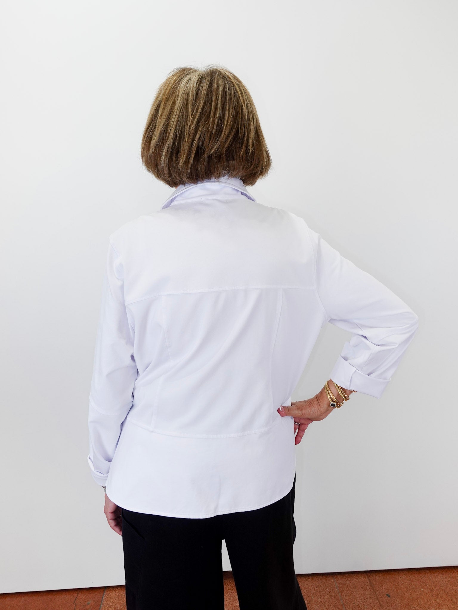 Person wearing a white shirt with long sleeves against a plain background