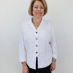 Woman wearing a white blazer with buttons against a plain background