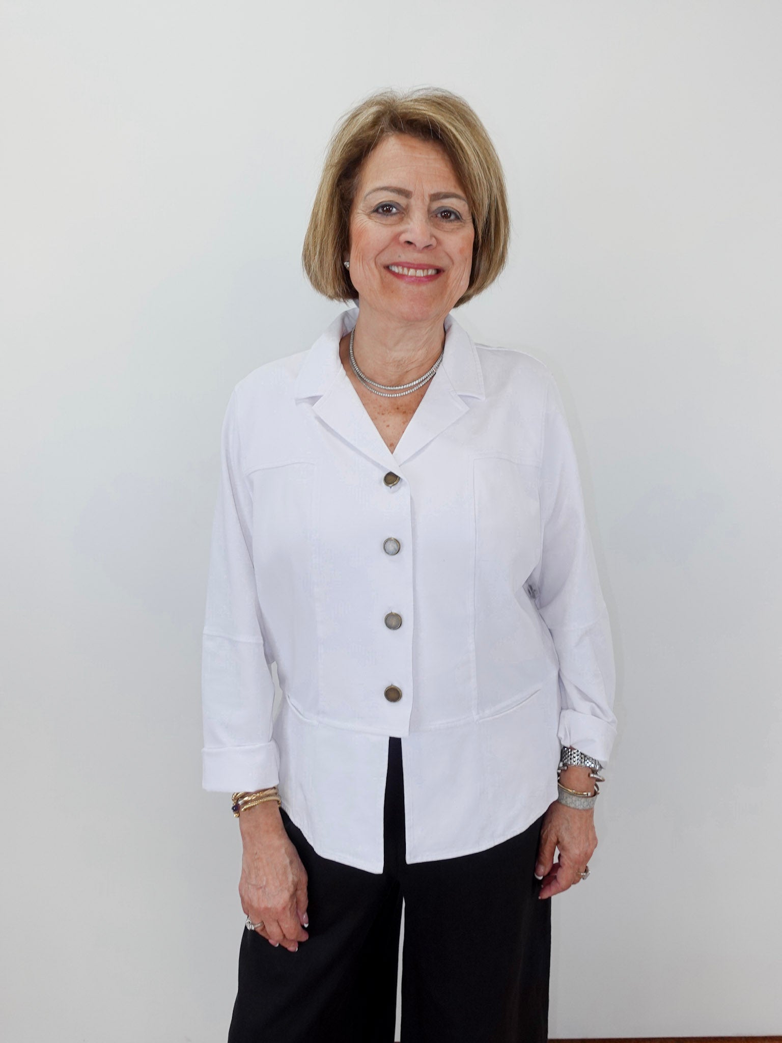 Woman wearing a white blazer with buttons against a plain background
