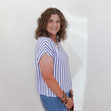 Woman wearing a striped shirt and jeans against a white wall