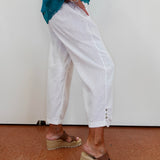 Person wearing white pants and brown sandals on a plain background