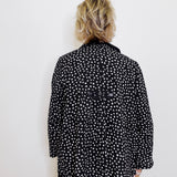 Person wearing a black polka dot jacket against a white background