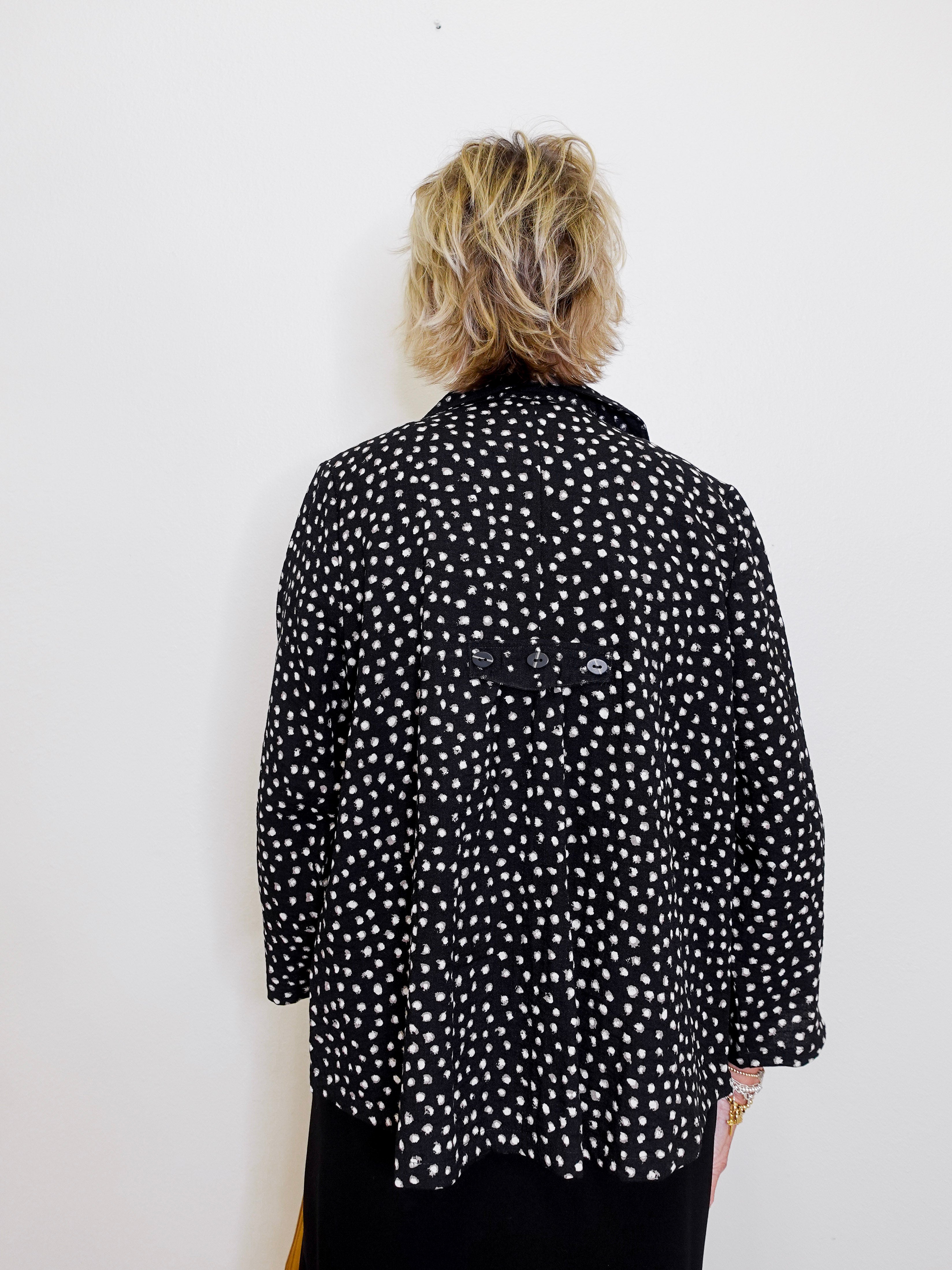 Person wearing a black polka dot jacket against a white background