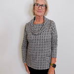 Person wearing a gray knitted sweater against a white background