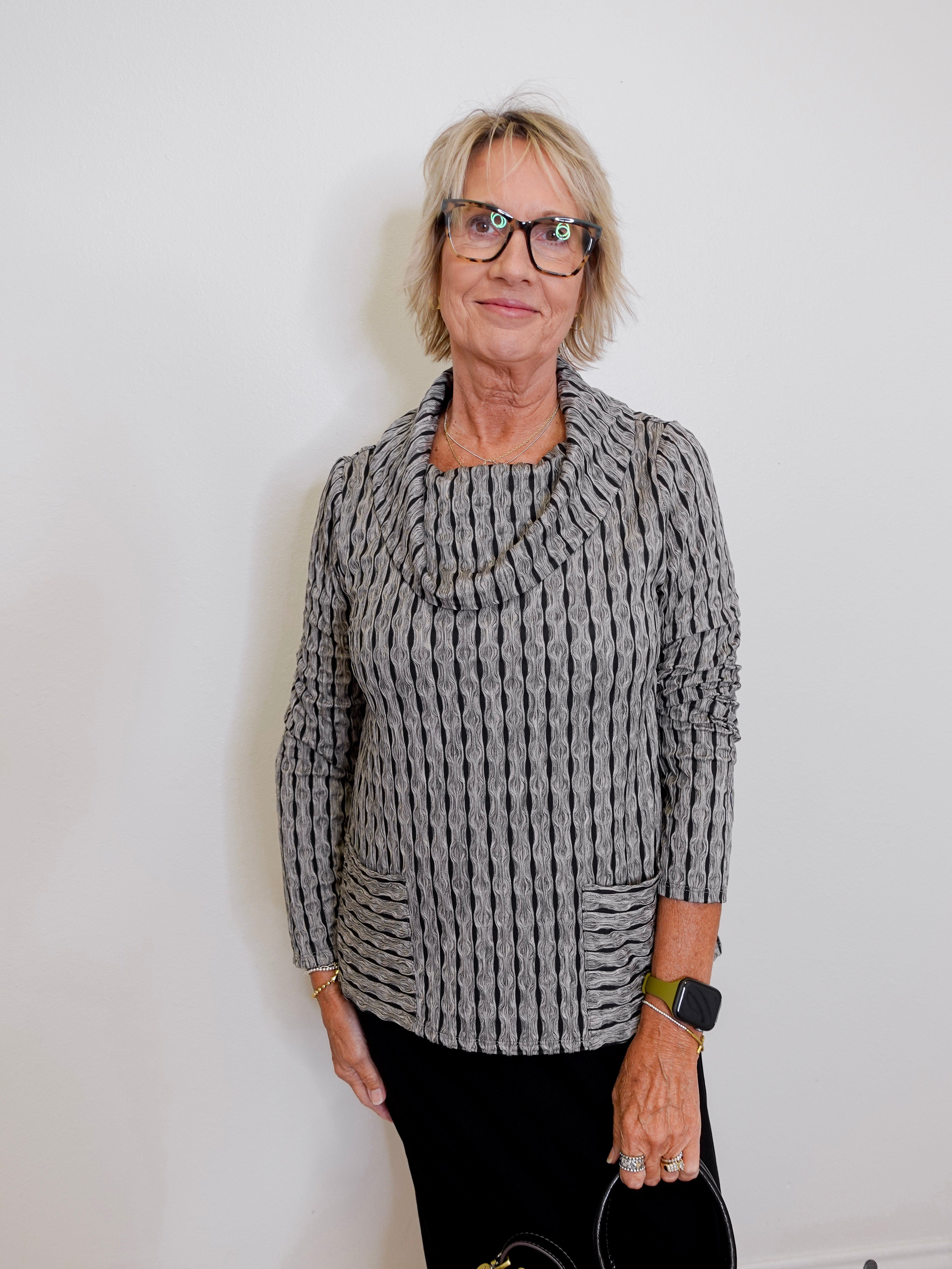 Person wearing a gray knitted sweater against a white background