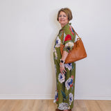 Woman wearing a floral dress with a brown bag against a white wall