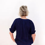 Person wearing a navy blue blouse with rolled-up sleeves on a white background