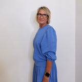 Woman wearing a blue outfit against a white wall