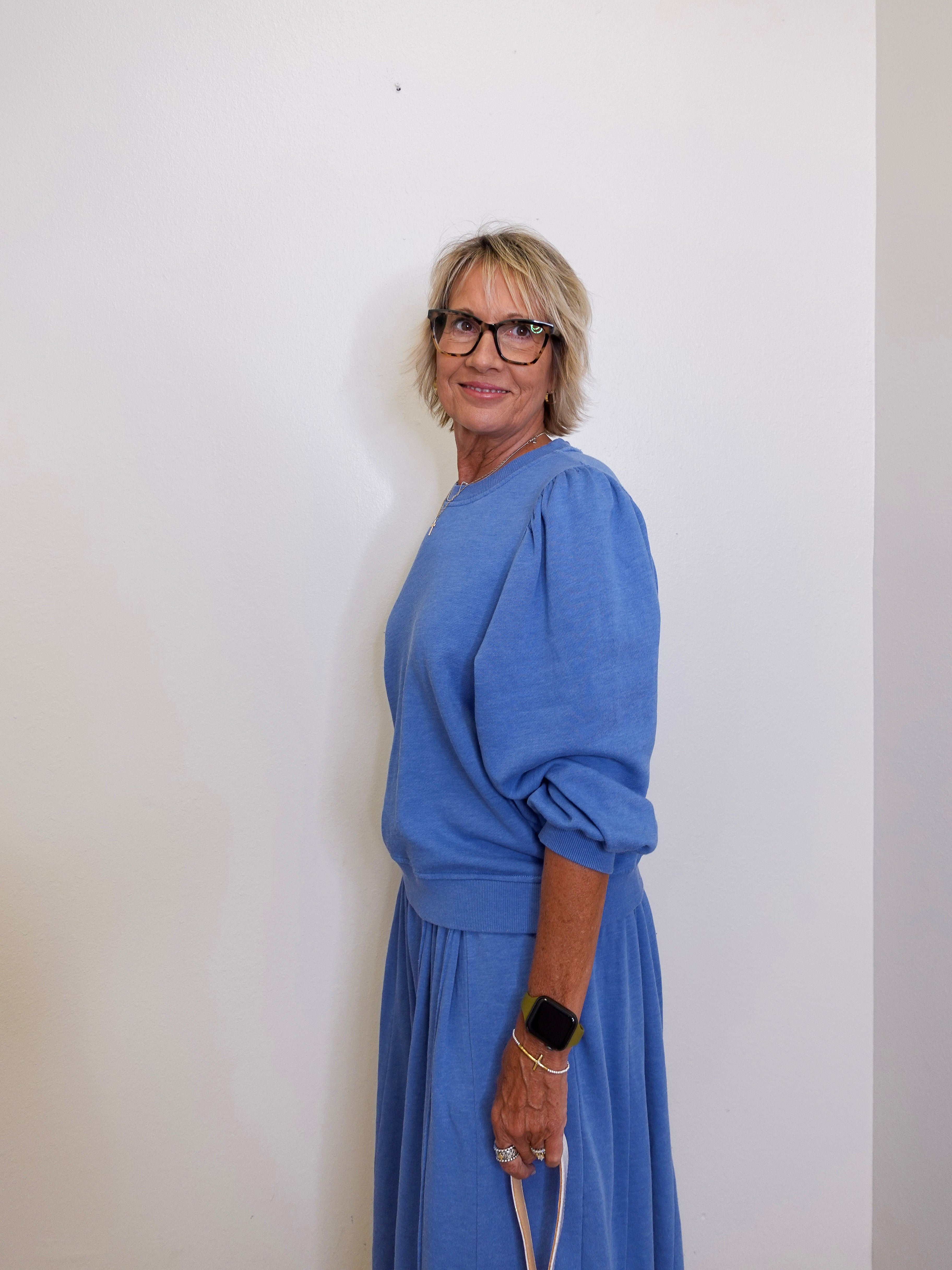 Woman wearing a blue outfit against a white wall