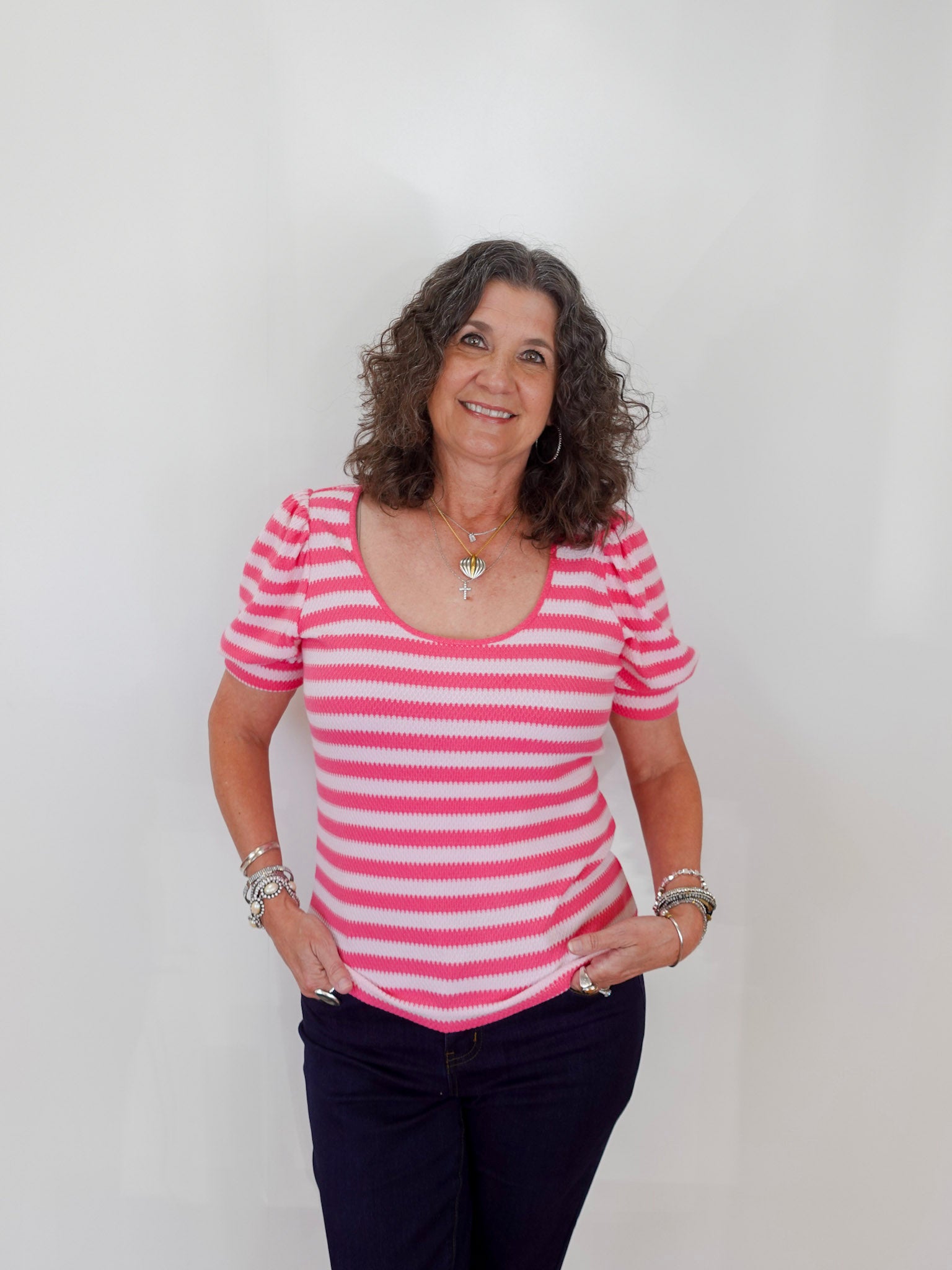 Woman wearing a pink and white striped shirt against a plain background