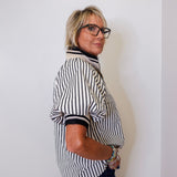 Person wearing a black and white striped shirt against a plain background
