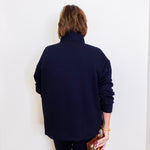 Person wearing a navy blue outfit holding a colorful clutch against a white background