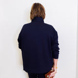 Person wearing a navy blue outfit holding a colorful clutch against a white background