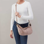 Person holding a beige handbag against a plain background