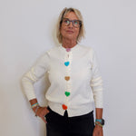 Woman wearing a white cardigan with colorful buttons against a plain background