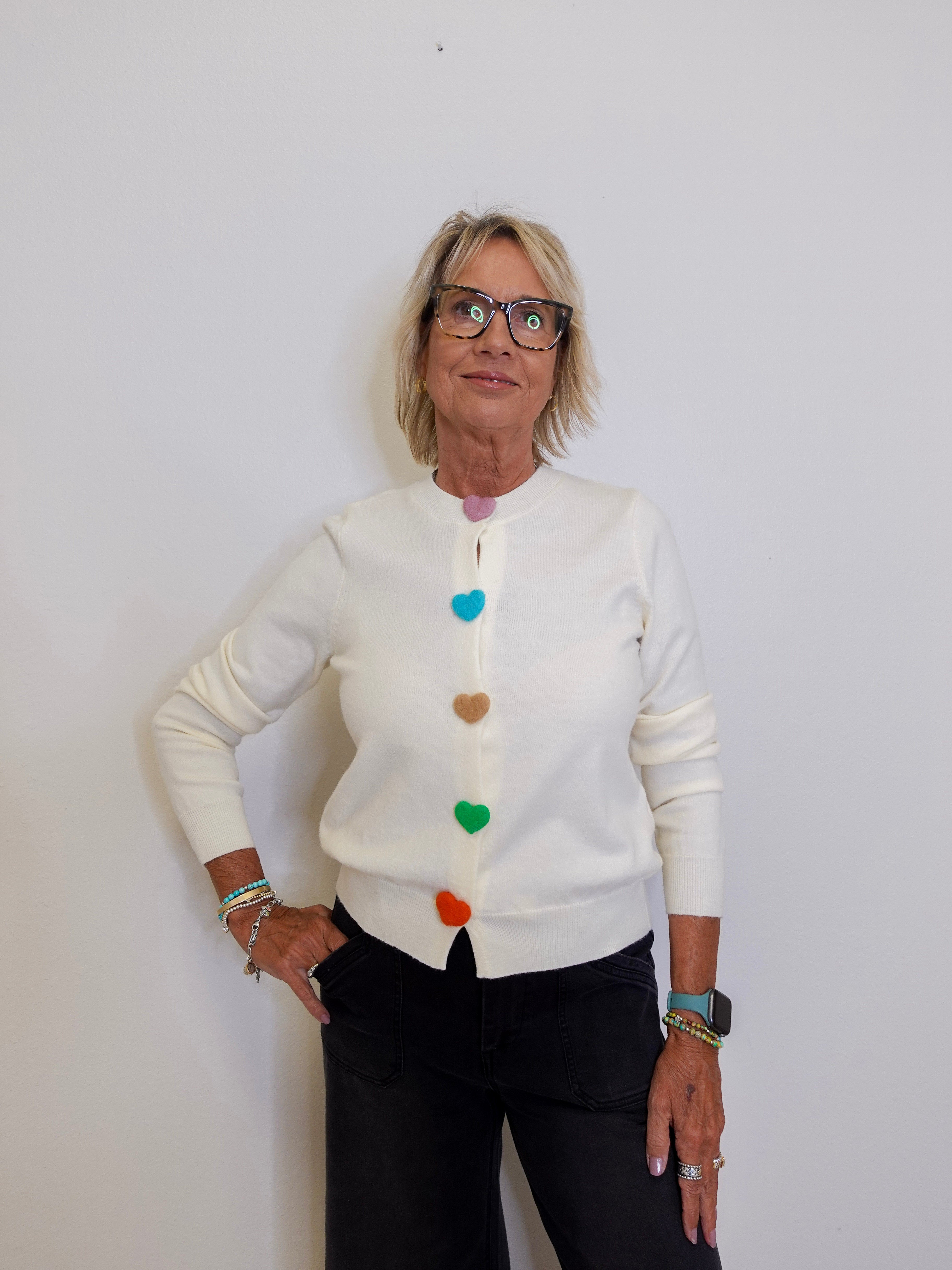 Woman wearing a white cardigan with colorful buttons against a plain background