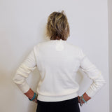 Person wearing a white sweater and black pants against a plain background