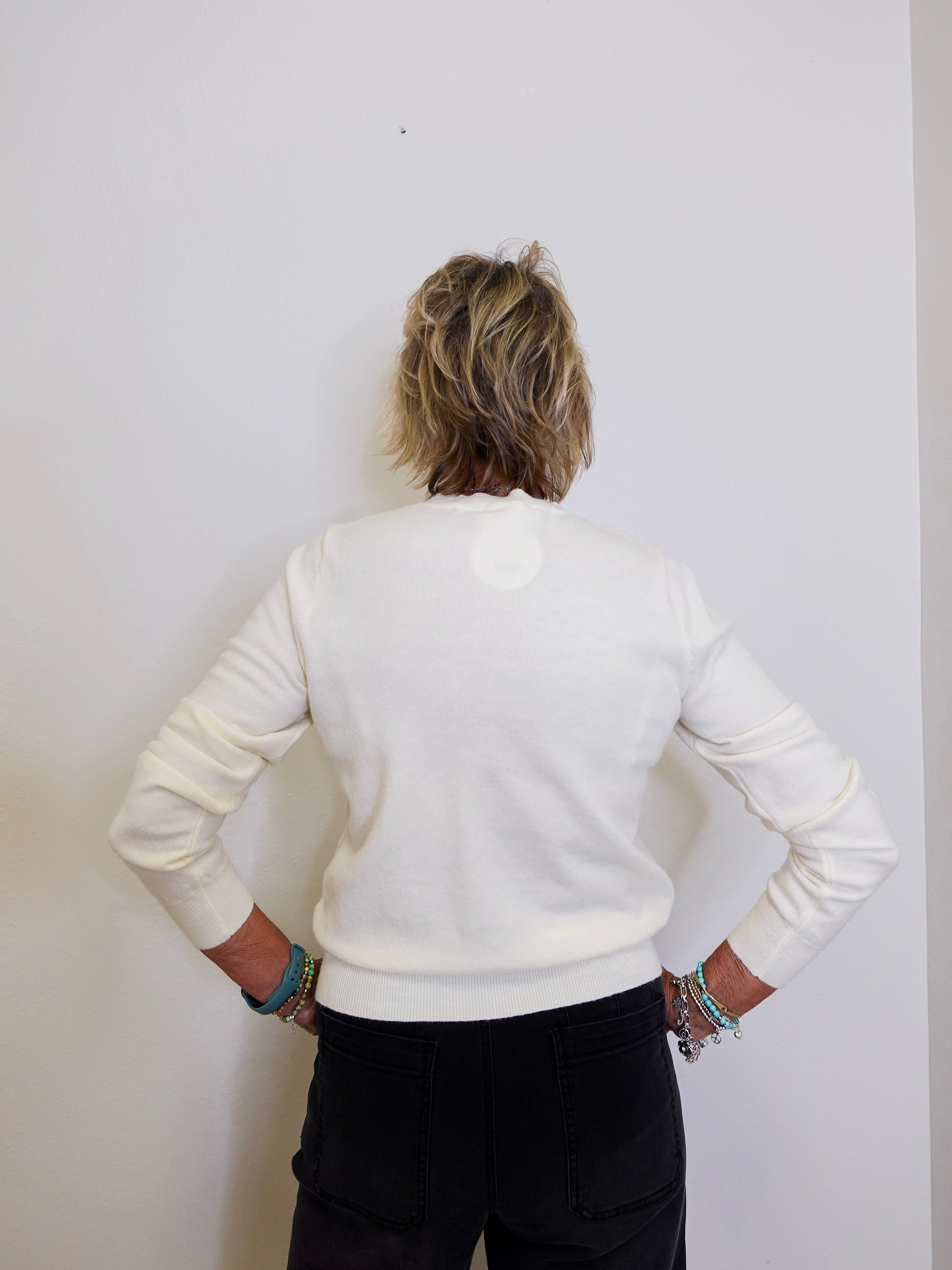 Person wearing a white sweater and black pants against a plain background