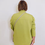 Woman wearing a green sweater in front a white background.