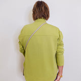 Woman wearing a green sweater in front a white background.