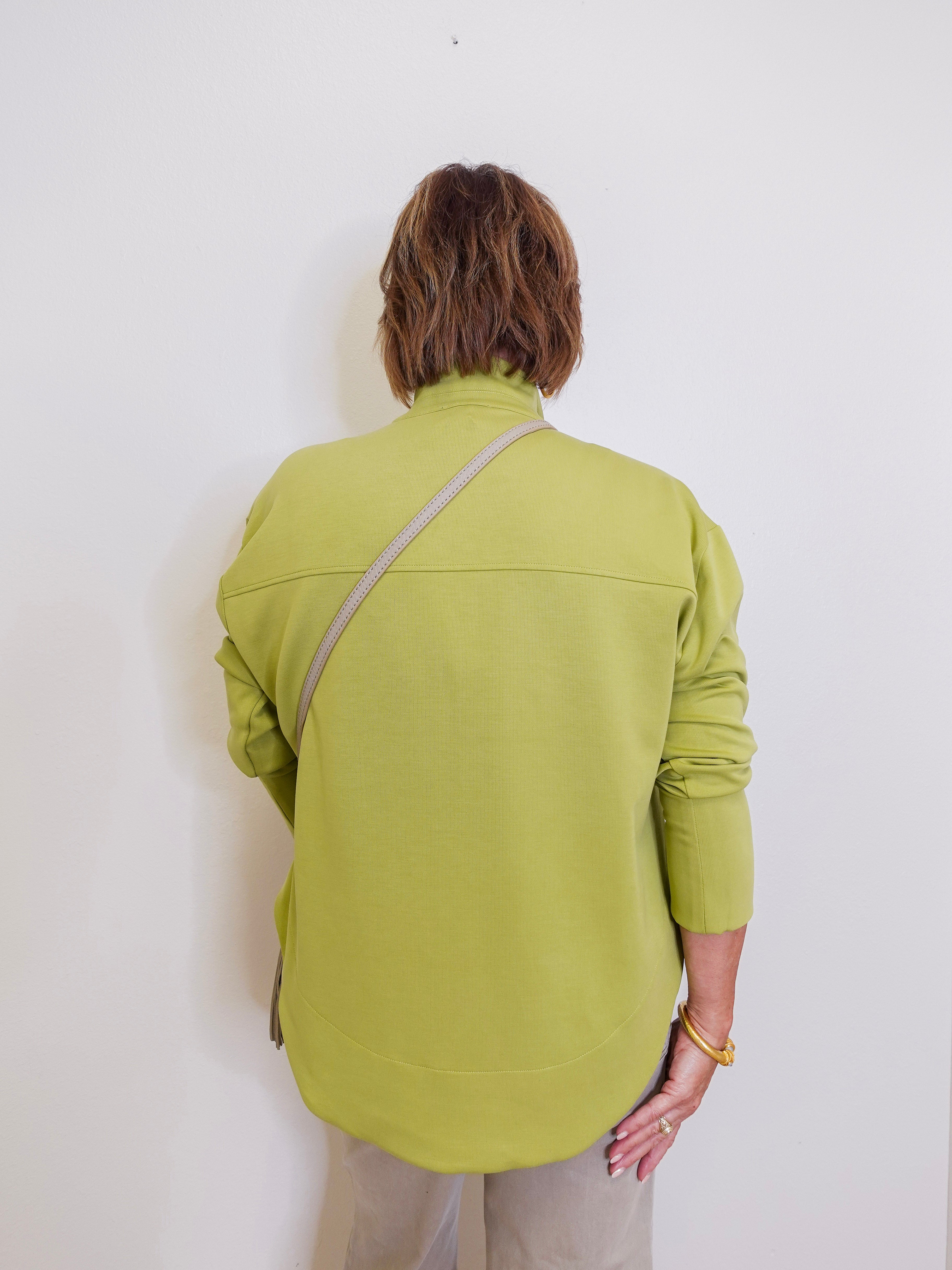 Woman wearing a green sweater in front a white background.