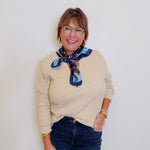 woman wearing a henley top with buttons that is tan in front of a white background. 