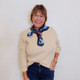 woman wearing a henley top with buttons that is tan in front of a white background. 