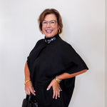 Woman wearing a black cape over a dark top with a white background