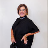 Woman wearing a black cape over a dark top with a white background