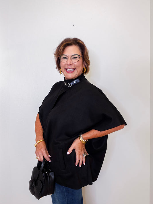 Woman wearing a black cape over a dark top with a white background