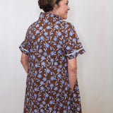 Woman wearing a brown floral dress against a white wall