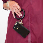 Person wearing a maroon jacket with a black keychain attached to it.