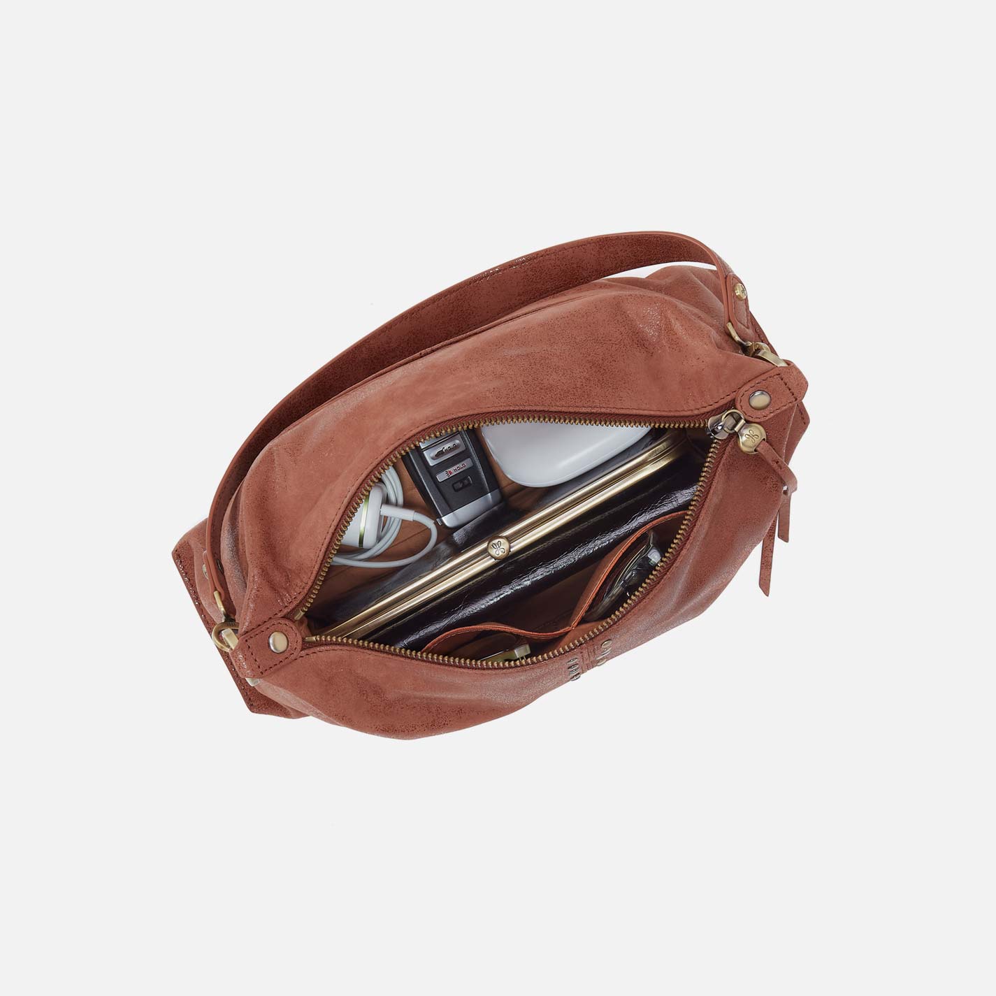 Brown leather bag with interior items on a white background