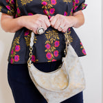 woman wearing a gray suede handbag with braided handle on a white background