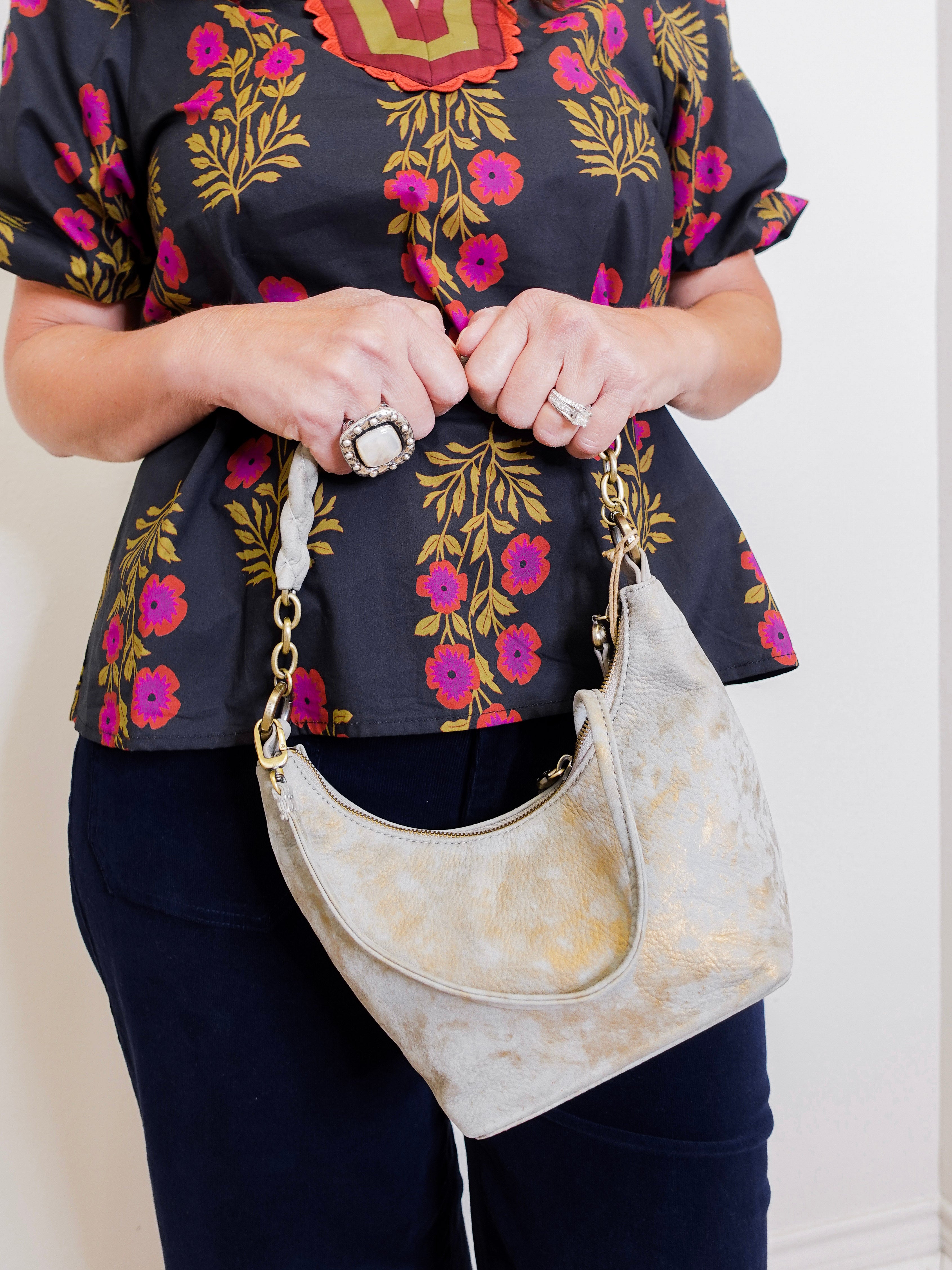 woman wearing a gray suede handbag with braided handle on a white background