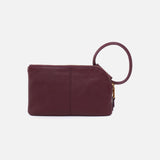 Maroon leather clutch with a ring handle on a light gray background