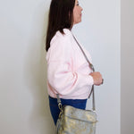 Woman holding a gray handbag against a white wall