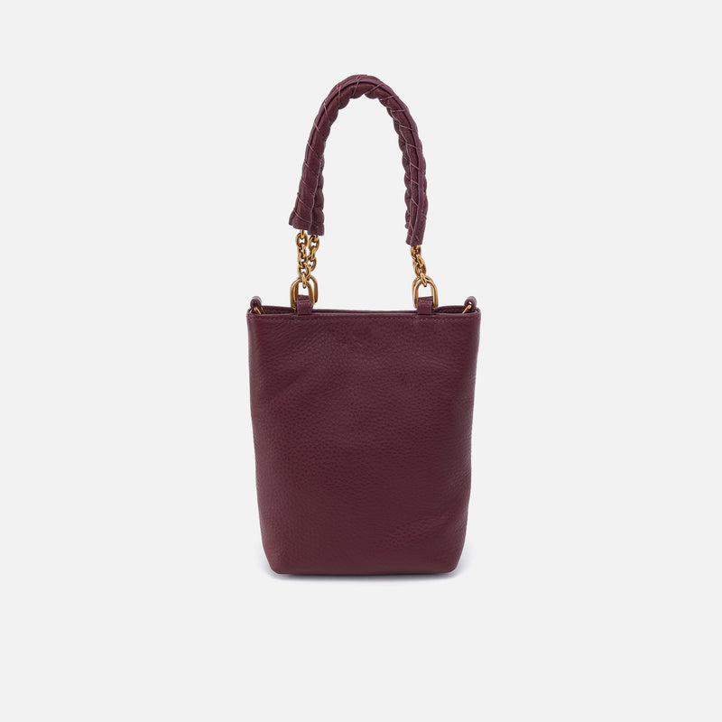 Burgundy handbag with braided handle on a light gray background
