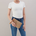 Person holding a woven clutch bag against a plain background