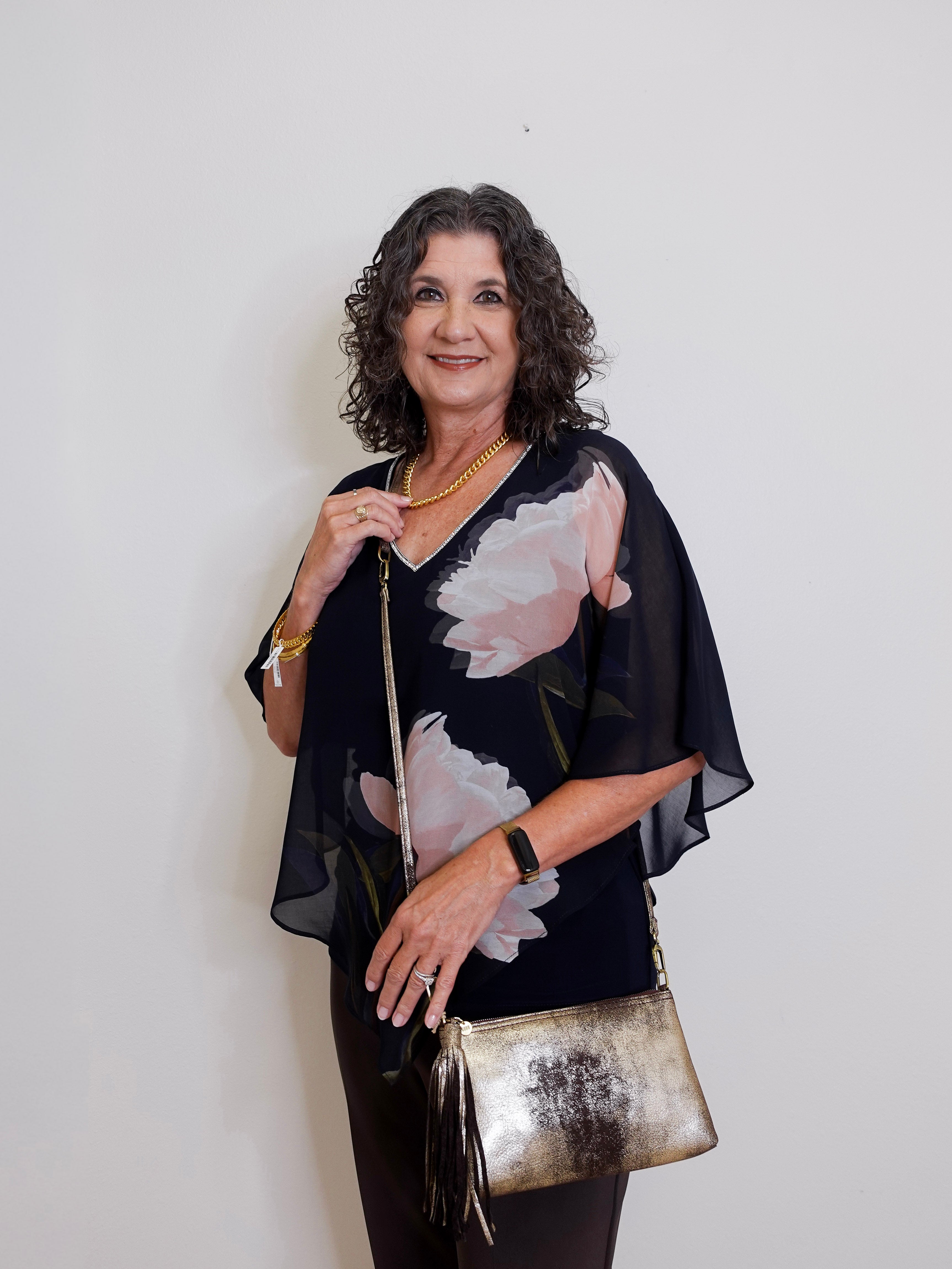 Woman holding a metallic handbag against a plain background