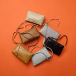 Set of six leather handbags in various colors on an orange background
