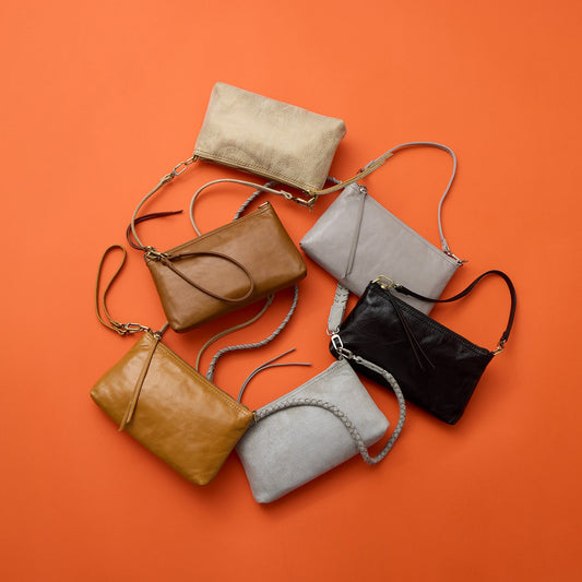 Set of six leather handbags in various colors on an orange background