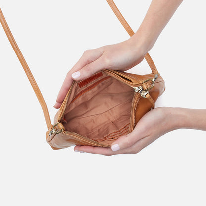 Brown handbag held open by a hand on a light background