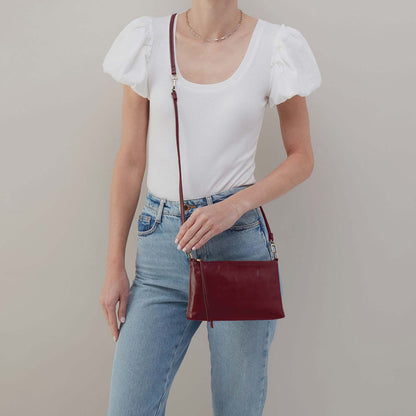 Person wearing a white top and blue jeans with a red handbag on a plain background