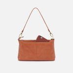 Brown leather handbag with a phone inside on a white background
