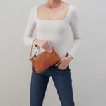 Person holding a brown leather clutch bag against a plain background