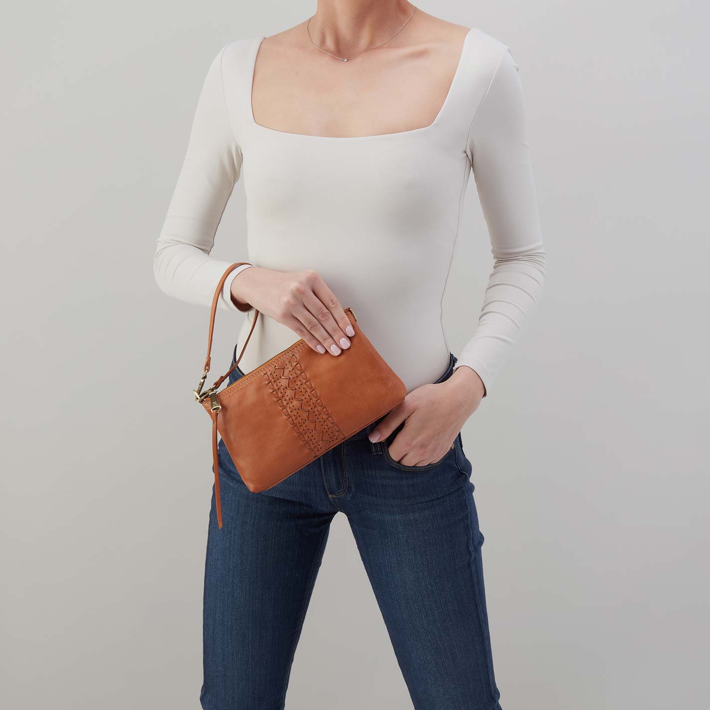 Person holding a brown leather clutch bag against a plain background