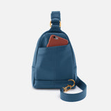Blue leather sling bag with a brown phone case on a light gray background