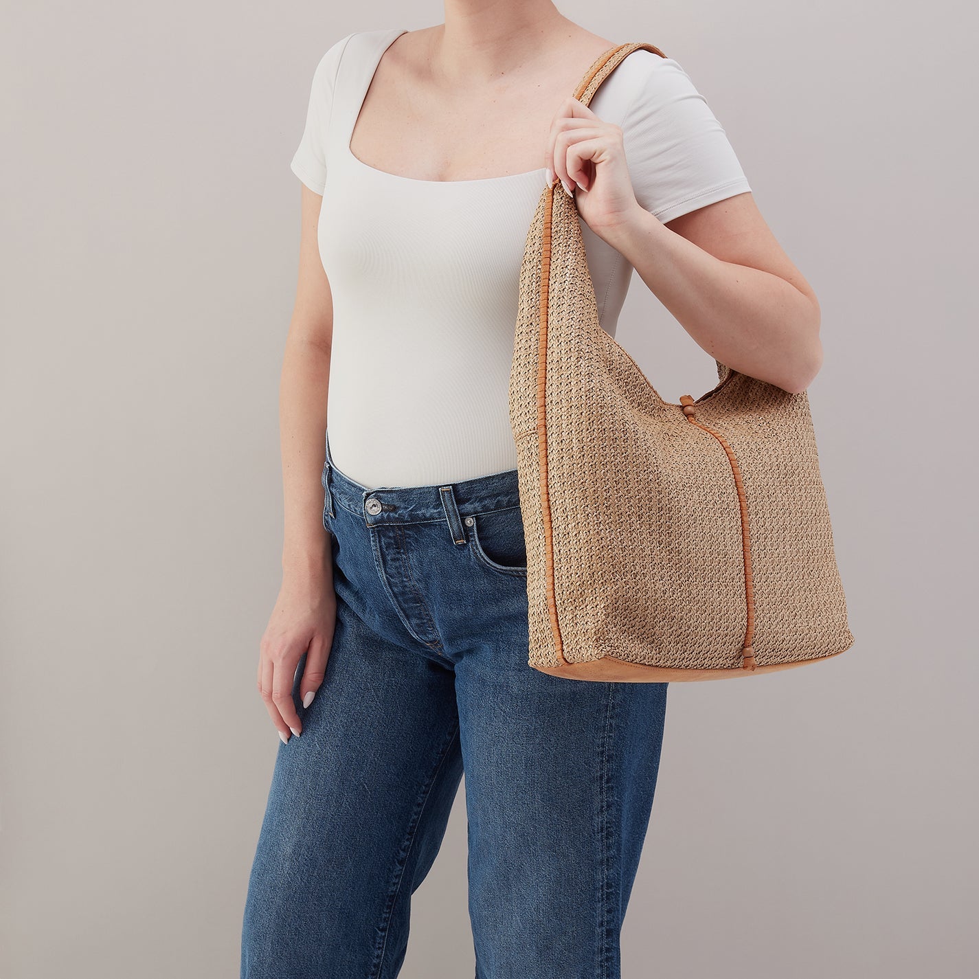 Person holding a woven bag against a plain background